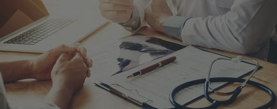 Two people looking over documents and a stethoscope